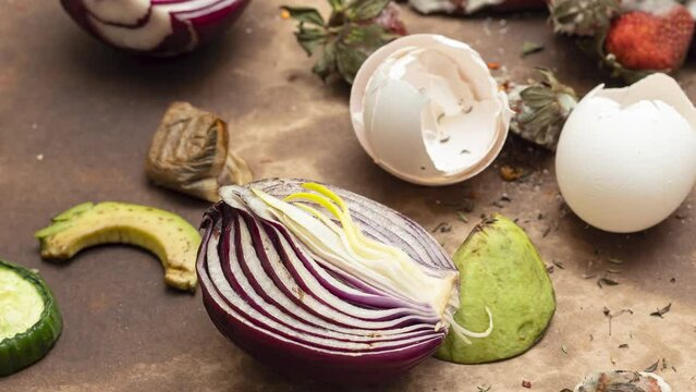 Panning, slider shot of rotten food waste on soiled cardboard. Spoiled vegetables, fruits and eggshells , food waste or composting concept.
