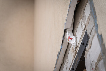 Facade plaster bark beetle beige flakes off from polystyrene foam insulation. Non-compliance with work technology