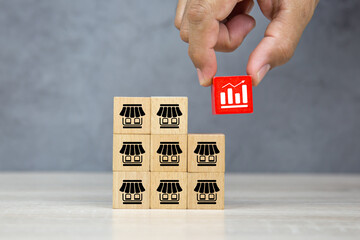 Close-up hand choose graph on wooden block stack with franchise business store icon for franchising...
