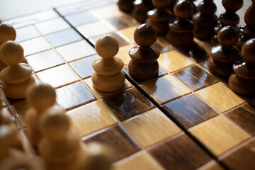 Schwarzer und weisser Bauer stehen sich auf Schachbrett aus Holz gegenüber Schach