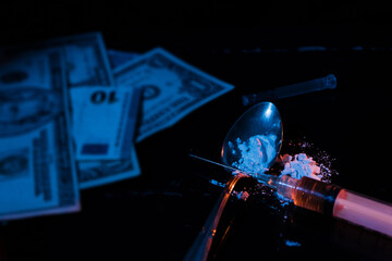 Money and drugs. Banknotes and simulation of drugs such as heroin or cocaine on a black, dimly lit surface. High view. Concept of illegal substances, prohibited drugs, illegal traffic.