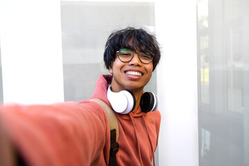 Asian adolescent male taking selfie with phone looking at camera. Teen boy college students take...