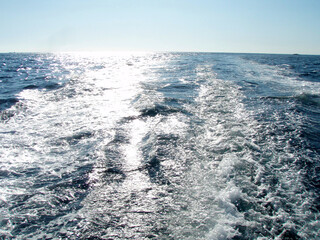 A wake that was a bubble of a fast moving ship shining in the backlight of the sun.