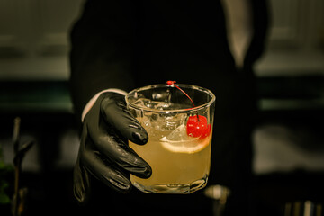 Barman hand hold the bourbon sidecar cocktail on the bar counter