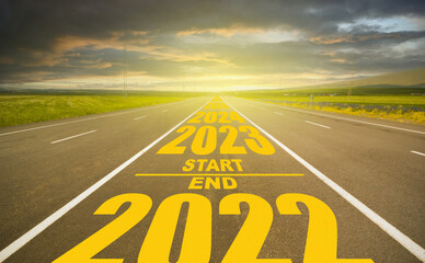 2022 end and start 2023 written road. Year numeral 2023 at dramatic sunset and on empty road. Goal...