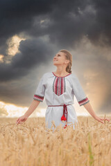 girl in an embroidered shirt on a wheat field and a sunset sky