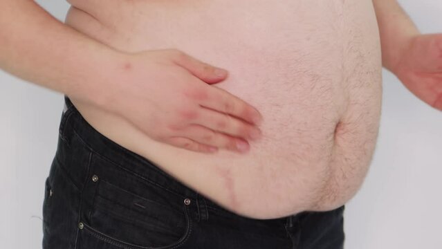 
Close up male belly, overweight. The fat man beats and claps his hands on his bare, large belly, the fat folds shake. Isolated on a white background.