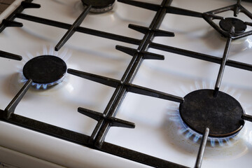 two burning burners of a gas white kitchen stove