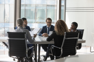 Fototapeta na wymiar Diverse millennial business group brainstorming, at conference table. Startup leaders, project investors meeting, analyzing marketing reports, negotiating on investment, deal
