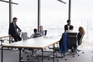 Two diverse business team gathering separately in modern office interior with panoramic window...