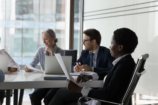 Diverse Business Team Working Together, Discussing Project At Table In Meeting Room. Group Of Coworkers, Investors, Stakeholders Analyzing Marketing Financial Reports, Discussing Startup