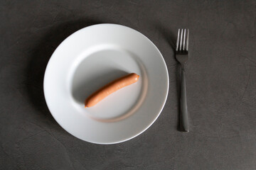 A person is forced to eat one sausage with a fork due to lack of money and livelihood due to sanctions and hunger caused by the war.