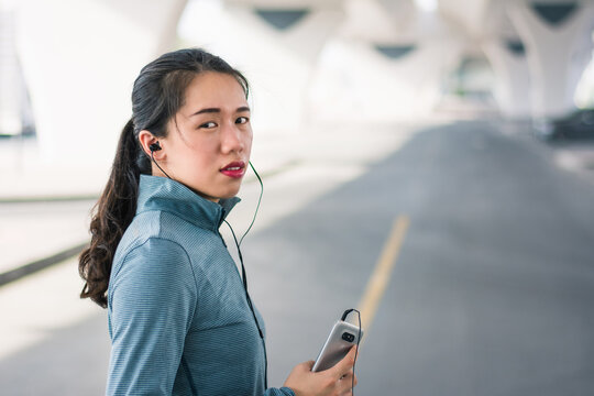 Woman taking rest from an outdoors workout and running outdoors listening to music