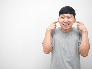 Fototapeta premium Man gesture plug finger close his ear and looking at copy space white background
