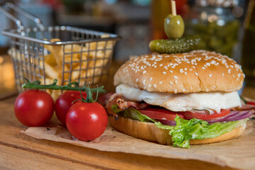 Burger with chicken breast, lettuce leaves, tomatoes, pickles and hot peppers