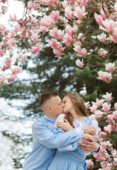 Beautiful couple kissing under blooming magnolia tree. Vintage villa at background