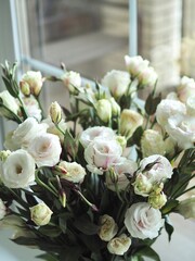 Beautiful spring delicate bouquet of white flowers of lisianthus, eustoma on the window close-up. Mother's day card. Wedding concept. Floristry, floral studio