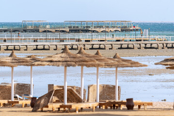 Empty beach in Egypt. Loungers and jetties without people. Holidays in Egypt. Beach at low tide.