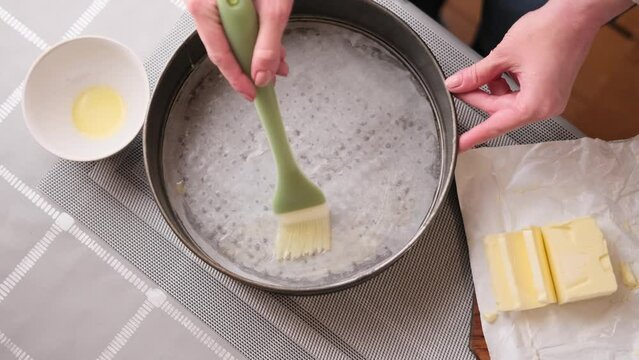 Close-up video of Woman buttering a cake pan for baking cake