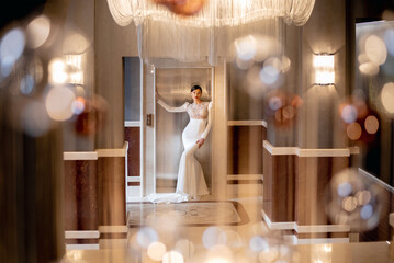 Bride in wedding dress posing next to elevator in hotel