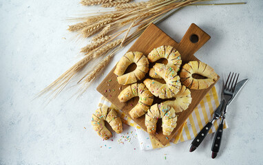 delicious fragrant homemade dessert, fresh bagels with cinnamon and wheat spikelets, cotton towel on a light background.