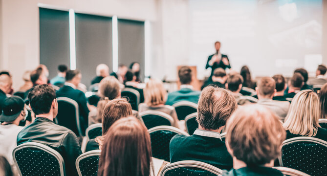 Speaker giving a talk in conference hall at business event. Rear view of unrecognizable people in audience at the conference hall. Business and entrepreneurship concept.