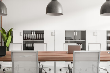 Light office room interior with seats, table with laptop and shelf