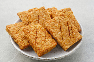 Tempeh, Tempe Goreng or Fried tempeh is Indonesia traditional food, made from fermented soybean seeds wrapped in banana leaves. Salty and savory, served as a side dish or snack. Served on plate.
