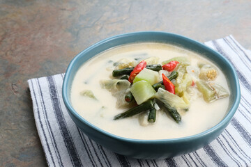 Sayur Lodeh or vegetable soup with coconut milk, delicious of traditional indonesian food. Consists of chayote, long beans, eggplant, cabbage and coconut milk. Served in bowl, close up.

