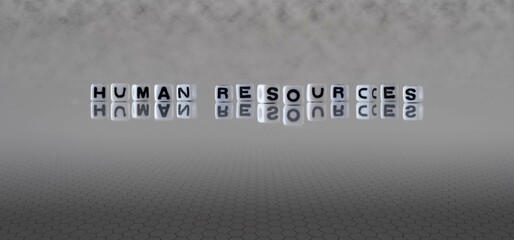 human resources word or concept represented by black and white letter cubes on a grey horizon background stretching to infinity