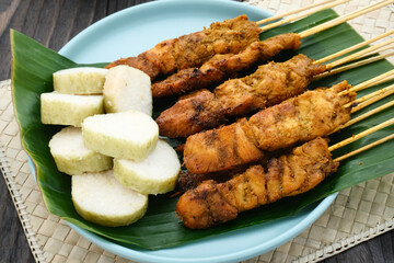Chicken satay (sate ayam) with Lontong and peanut sauce. One of the popular street food in Indonesia. Selective focus.
