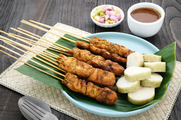 Chicken satay (sate ayam) with Lontong and peanut sauce. One of the popular street food in Indonesia. Selective focus.
