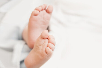 Obraz na płótnie Canvas two baby feet on the background of white bed linen. copy space. Ukrainian newborn. baby's little toes. top view