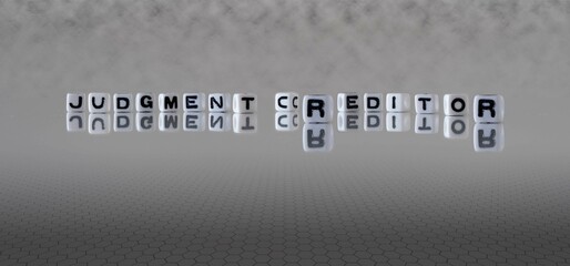 judgment creditor word or concept represented by black and white letter cubes on a grey horizon...