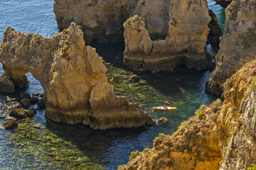 Fototapeta na wymiar Panoramic view with Cliff, rocks and kayak boat on sea at Ponta da Piedade near Lagos, Algarve, Portugal