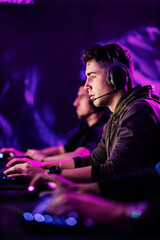 A professional gamer playing tournament with teammates in gaming room.