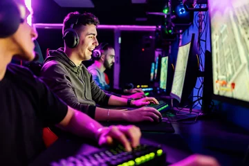 Fotobehang Gaming Happy gamer winning tournament in video game while sitting in dark gaming room.  © Dusan Petkovic