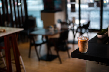 Close-up plastic glass of iced coffee with milk on the table