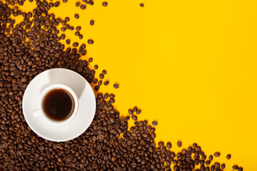Coffee cup and roasted beans on yellow background