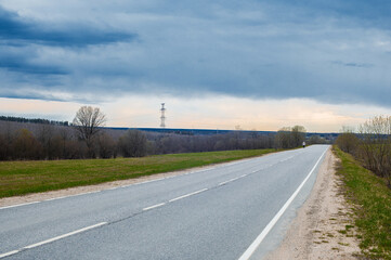Fototapeta na wymiar road in the countryside background landscape with trees and big green field and blue sky and white clouds