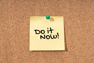 Do it now message on yellow note on cork board