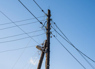 electric wires and a street lamp on an old wooden pole support against a background of blue sky...