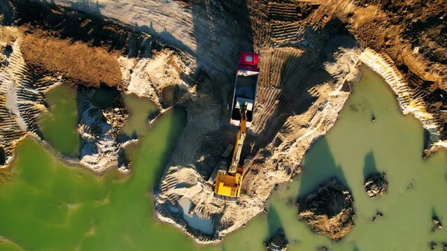 Top down view of an excavator loading sand into a dump truck. Sand quarry. Mining concept. 
