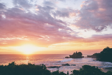 Beautiful balinese landscape. Ancient hinduism temple Tanah lot on the rock against sunset sky. Bali Island, Indonesia.