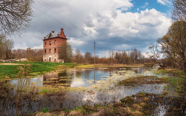 Fototapeta premium Panorama of the Izvarka river on a cloudy May day. The old Trout tower in the family estate of N.K. Roerich. Izvara. Leningrad region, Russia.