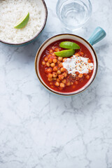 Indian chana masala or chole masala with basmati rice, flat lay on a light-grey marble background, vertical shot, copy space