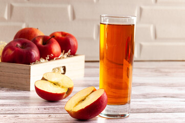 Red raw apple in basket with glass of apple juce. Simple composition. Box with apple before white wall. The half of apple. Selective focus.