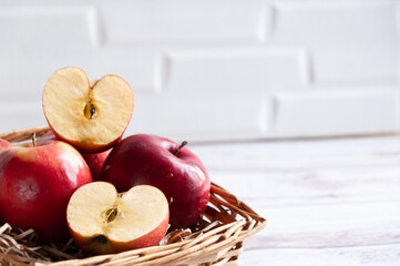 Fresh red apples in a wicker basket. Apples close-up with a cut slice. Wicker old basket with apples close-up. Selective focus