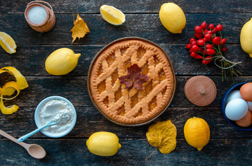 Delicious lemon tart,  pie with cooking ingredients on the wooden table, fresh lemons fruits around	