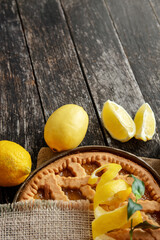 Delicious lemon tart,  pie with cooking ingredients on the wooden table, fresh lemons fruits around	